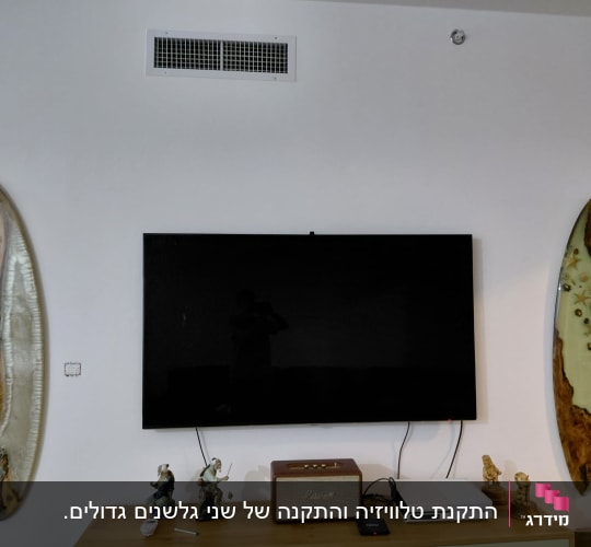 טלוויזיה תלויה על קיר בסלון לצד אלמנטים דקורטיביים מעוצבים